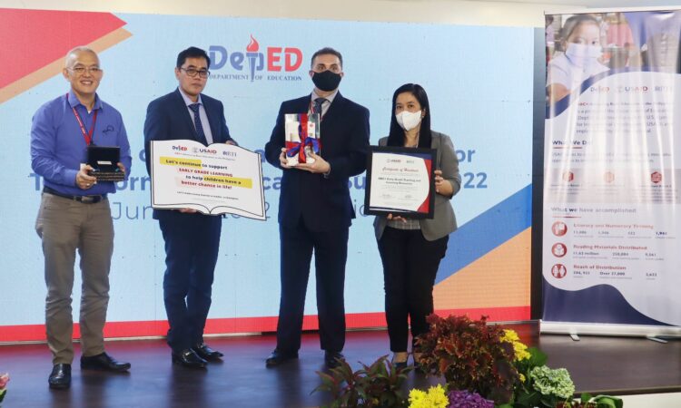 USAID Director of the Regional Financial Services Center Bret Campbell (second from right) joins Department of Education Undersecretaries Diosdado San Antonio and Nepomuceno Malaluan, and ABC+ Chief of Party Ina Aquino in the ceremonial handover to DepEd of USAID-developed early grade learning and teaching resources in Baguio City.