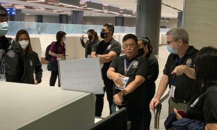 Customs Deputy Collector Dr. Jesus Llorando and CBP Officer Gerard Bradley discuss the procedures for the X-ray machines for carry-on baggage.