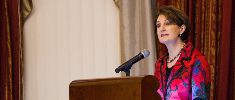 Ambassador MaryKay Carlson speaking behind a podium