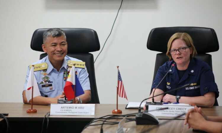 PCG Commandant Admiral Artemio Abu and USCG Pacific Strike Team commanding officer Stacey Crecy sitting at a table with small Philippine and U.S. flags in front of them.