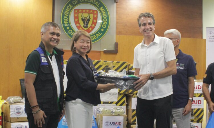USAID Philippines Mission Director Ryan Washburn (right) hands over U.S. government-donated protective gear and cleaning materials to Oriental Mindoro Governor Humerlito “Bonz” Dolor (left) and Calapan City Mayor Marilou Morillo (center).