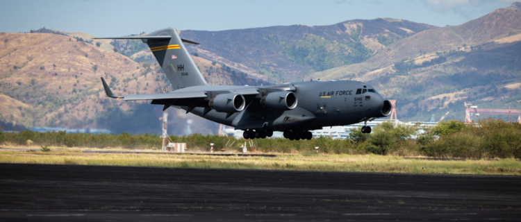 U.S. Air Force C-17 Globemaster III landing on a runway with a mountain in the background.