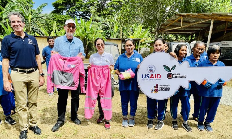 USAID Assistant Administrator Michael Schiffer (second from left) and USAID Philippines Mission Director Ryan Washburn (leftmost) hand over three additional garbage collection vehicles and newly designed uniforms to the Eco Warriors women waste collectors during a visit to Puerto Princesa City