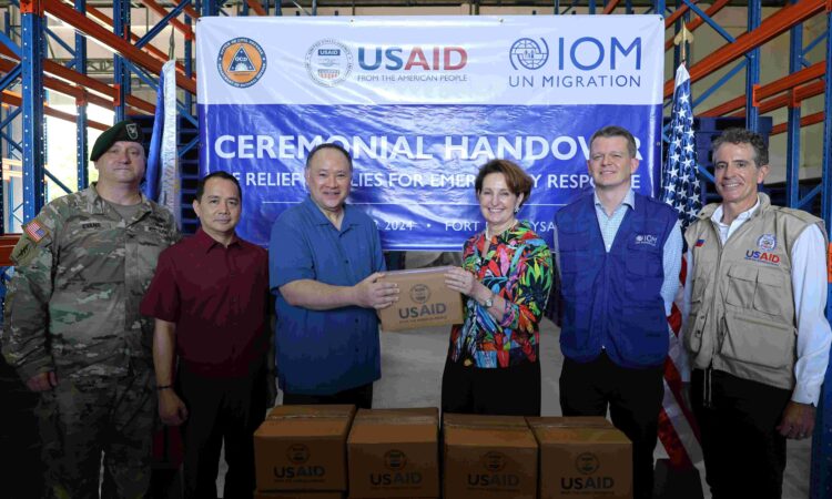 U.S. Ambassador MaryKay Carlson (third from right) leads the handover of emergency relief supplies to Secretary of National Defense Gilberto Teodoro Jr. (third from left) and Office of Civil Defense (OCD) Undersecretary Ariel Nepomuceno (second from left). Also in the photo are United States Agency for International Development (USAID) Philippines Mission Director Ryan Washburn (right), International Organization for Migration (IOM) Philippines Head of Programs Euan McDougall (second from right), and U.S. Embassy Senior Defense Official and Defense Attaché Col. Edward Evans. (left)