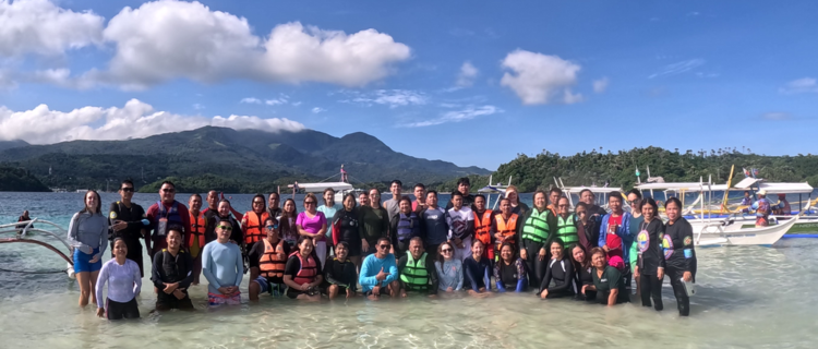 U.S. Peace Corps Volunteers and local community leaders posing together by the shallow waters in Puerto Galera, Oriental Mindoro.