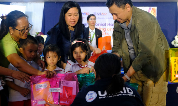 Young students receive U.S. government-donated learning kits from Philippine Department of Education (DepEd) Secretary Juan Edgardo Angara and USAID ABC+ Chief of Party Ina Aquino at Bula Central School in Camarines Sur on December 2.