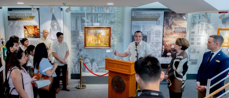 National Museum of the Philippines Director General Jeremy Barnes speaking behind a podium with Ambassador MaryKay Carlson standing beside him at the launch of the "Liberation of Manila: 80 Years of Remembrance Through Art" exhibit.
