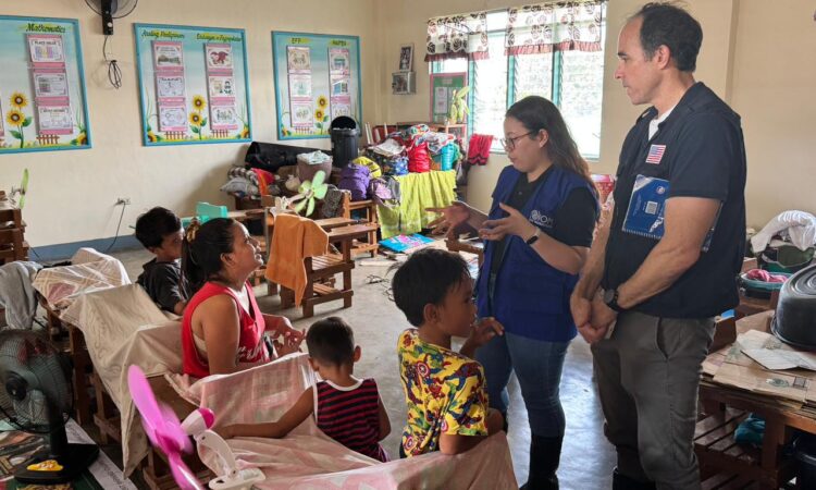 International Organization for Migration (IOM) Emergency Coordinator Kimberly Go Tian and U.S. Embassy Regional Disaster Advisor Joe Curry speak with a family at the Northville Elementary School evacuation center in Calumpit, Bulacan, on August 1.