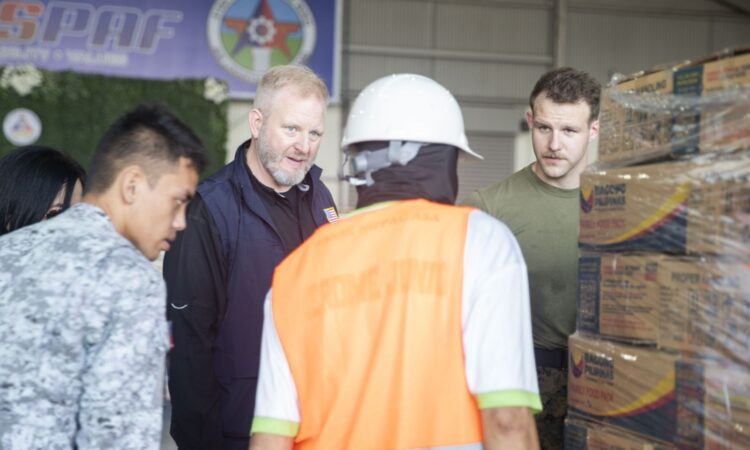 A U.S. State Department Regional Foreign Assistance Officer (left) and a U.S. Marine (right) discuss the transport of food packs with a Philippine Air Force servicemember and a Filipino contractor at Clark Air Base on November 13.